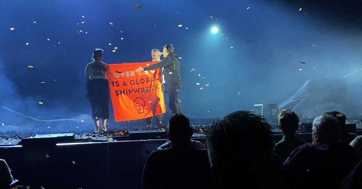 Two protestors take the stage with a confetti cannon and orange banner at 'The Tempest' on the West End.