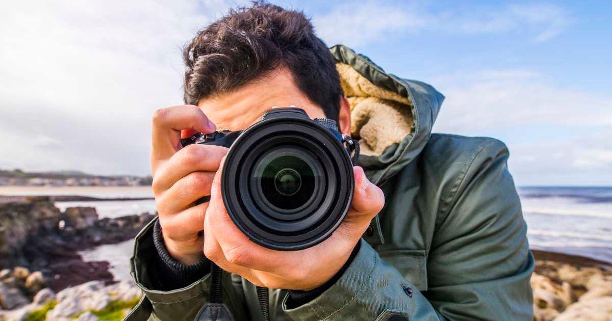 A young man using a DSLR camera to click a picture in nature. (Representative Cover Image Source: Getty Images | Mario Guti)