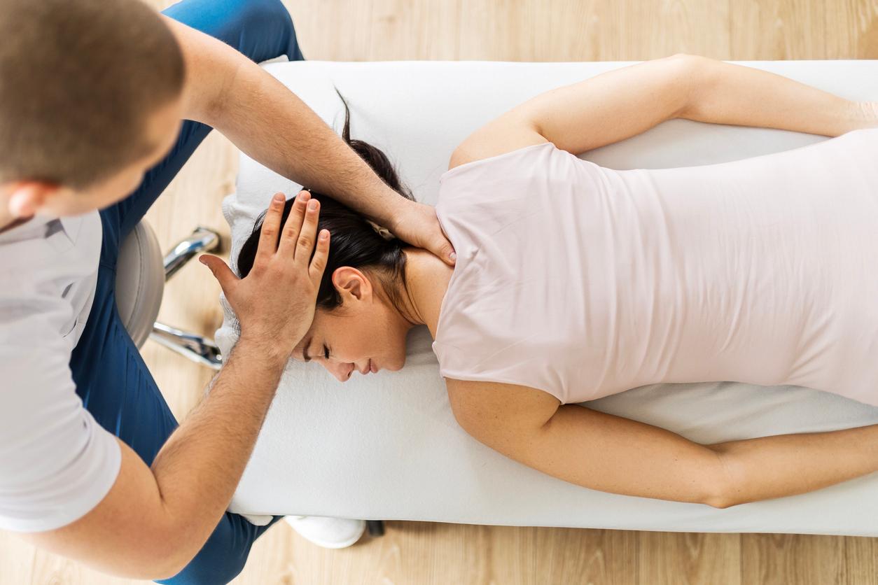 A male chiropractor adjusts a female patient's head and neck region.