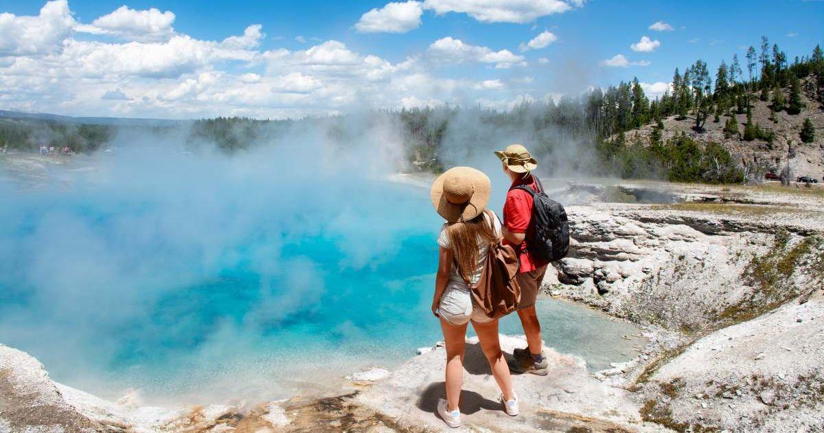 A couple enjoying the beautiful view of a geyser in Yellowstone National Park. (Representative Cover Image Source: Getty Images | MargaretW)