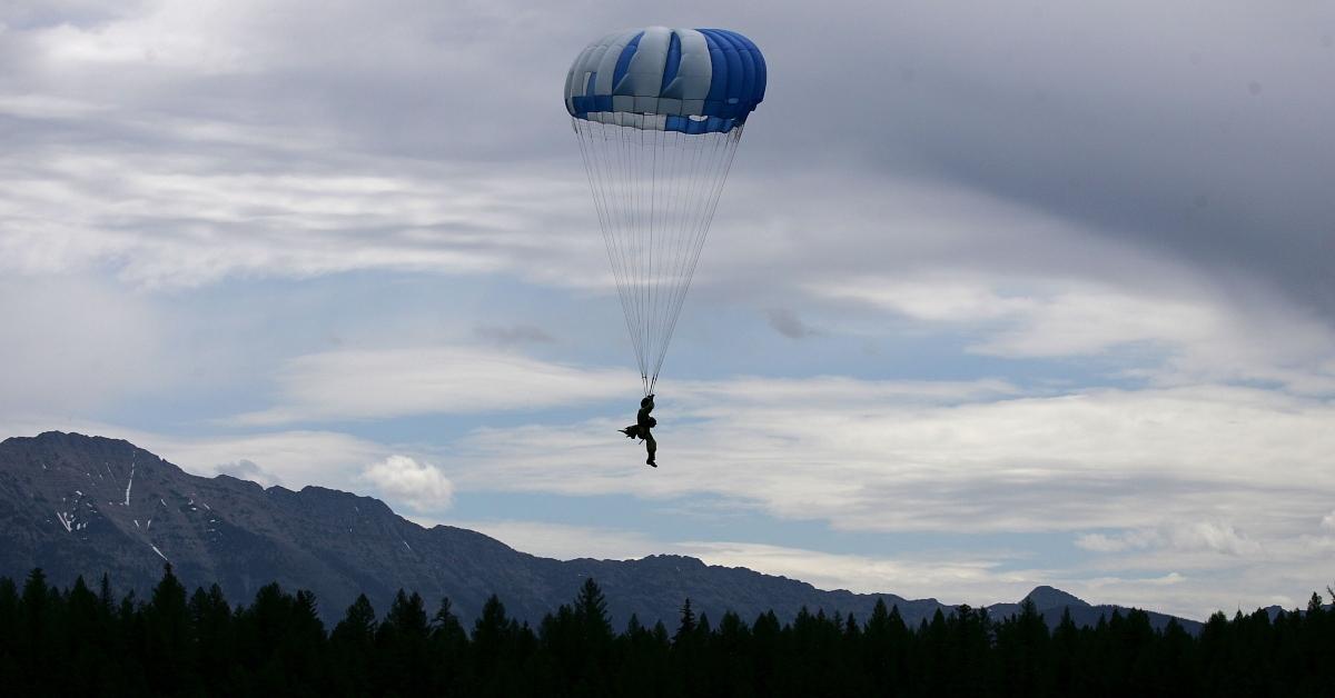 Smokejumper parachuting down into a forest. 