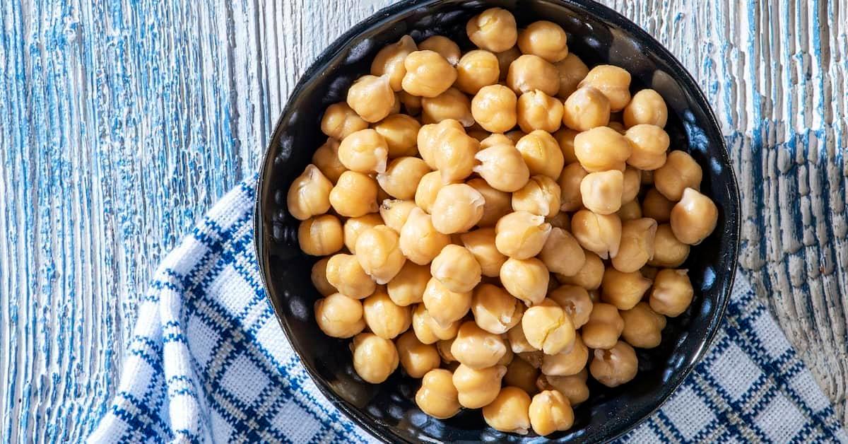 Boiled chickpeas in a bowl placed on a checkered blue and white cloth