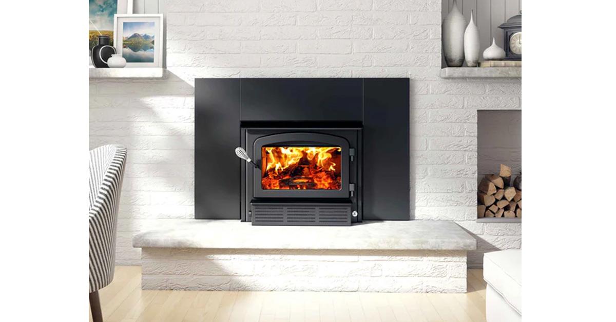 fireplace with wood stove insert and a fire inside in a white living room with a hearth