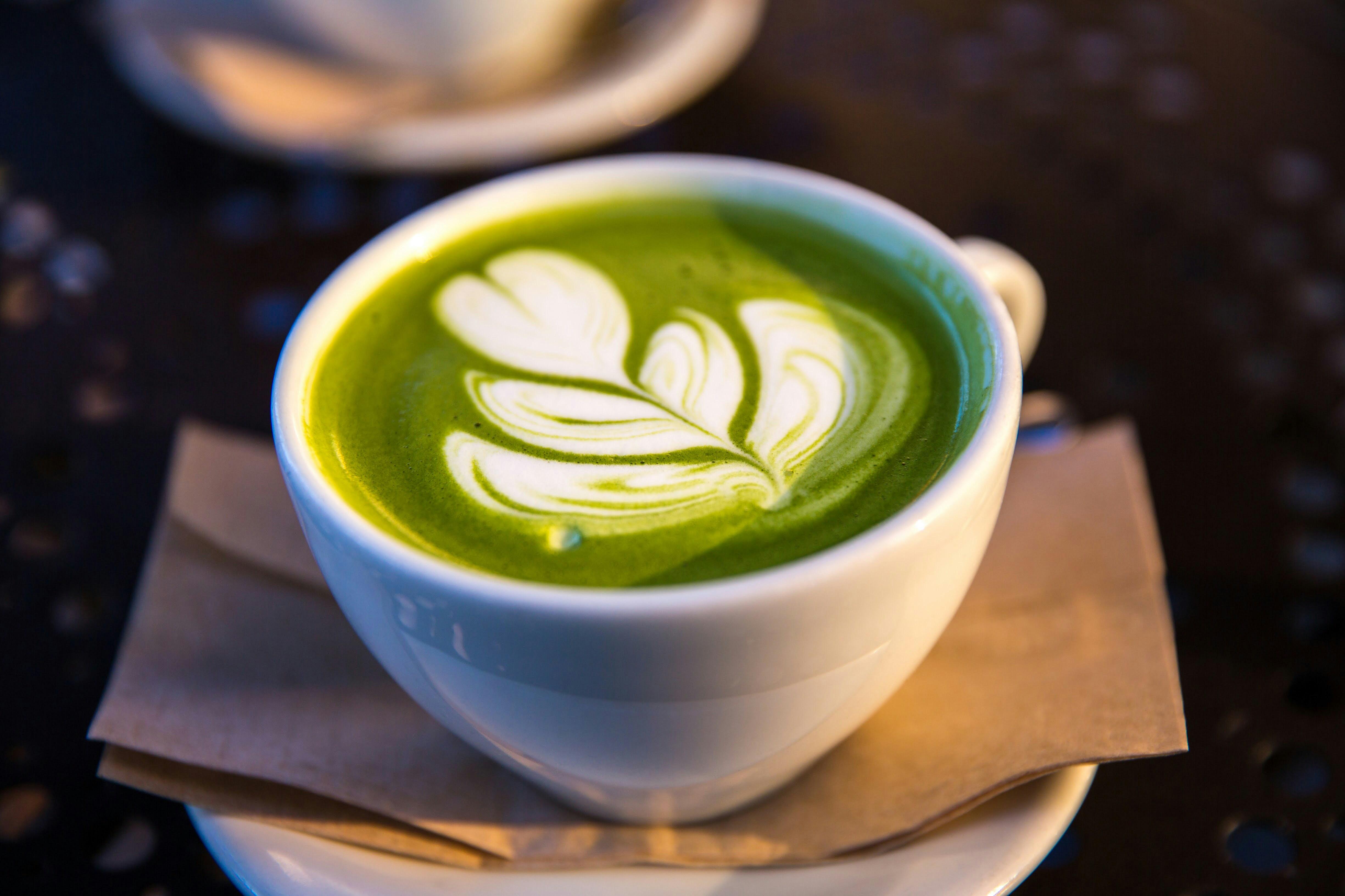 A cup of matcha is pictured atop a brown napkin on a table.