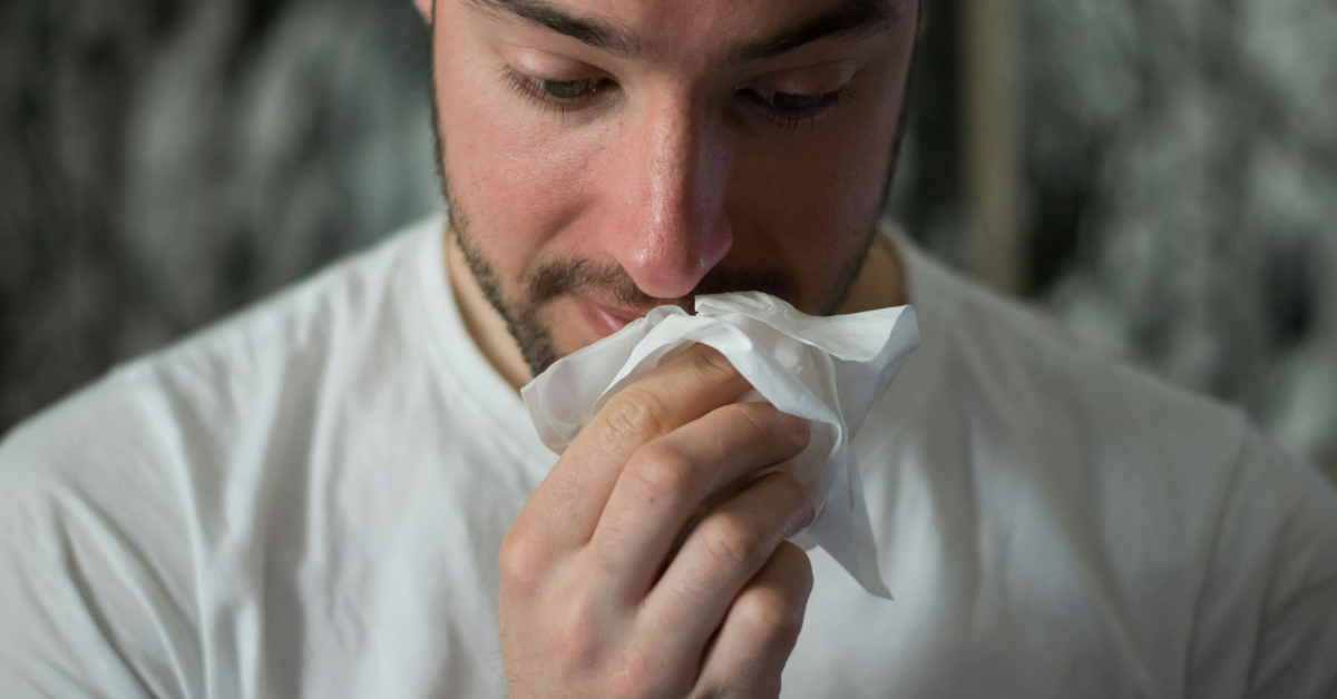 A nauseous man holds a napkin to his mouth