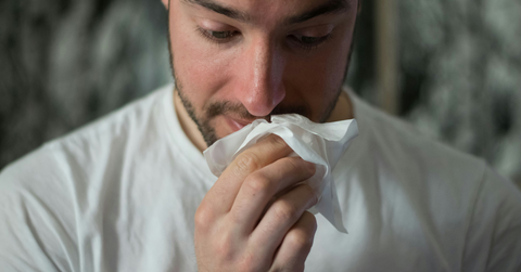 A nauseous man holds a napkin to his mouth