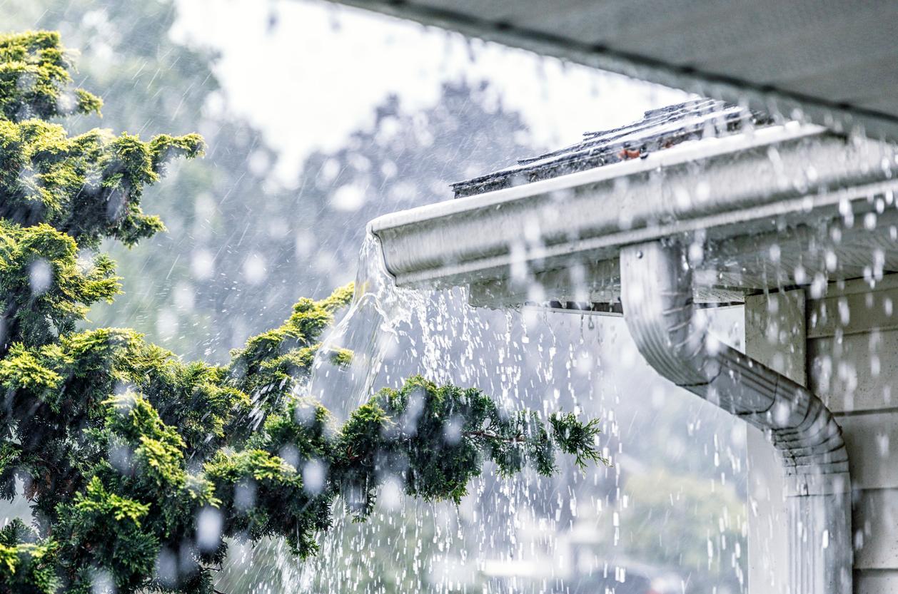 Torrential rain falling from the gutters of a home.