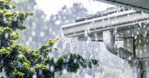 Torrential rain falling from the gutters of a home.