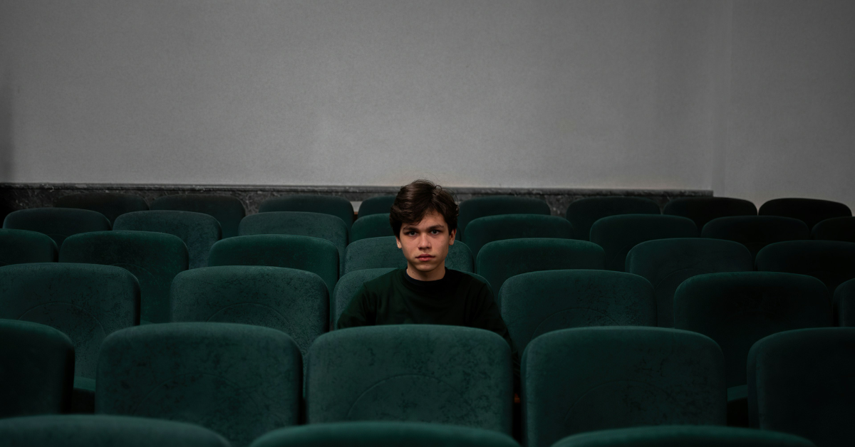 A person sits alone in the middle of an empty theatre 