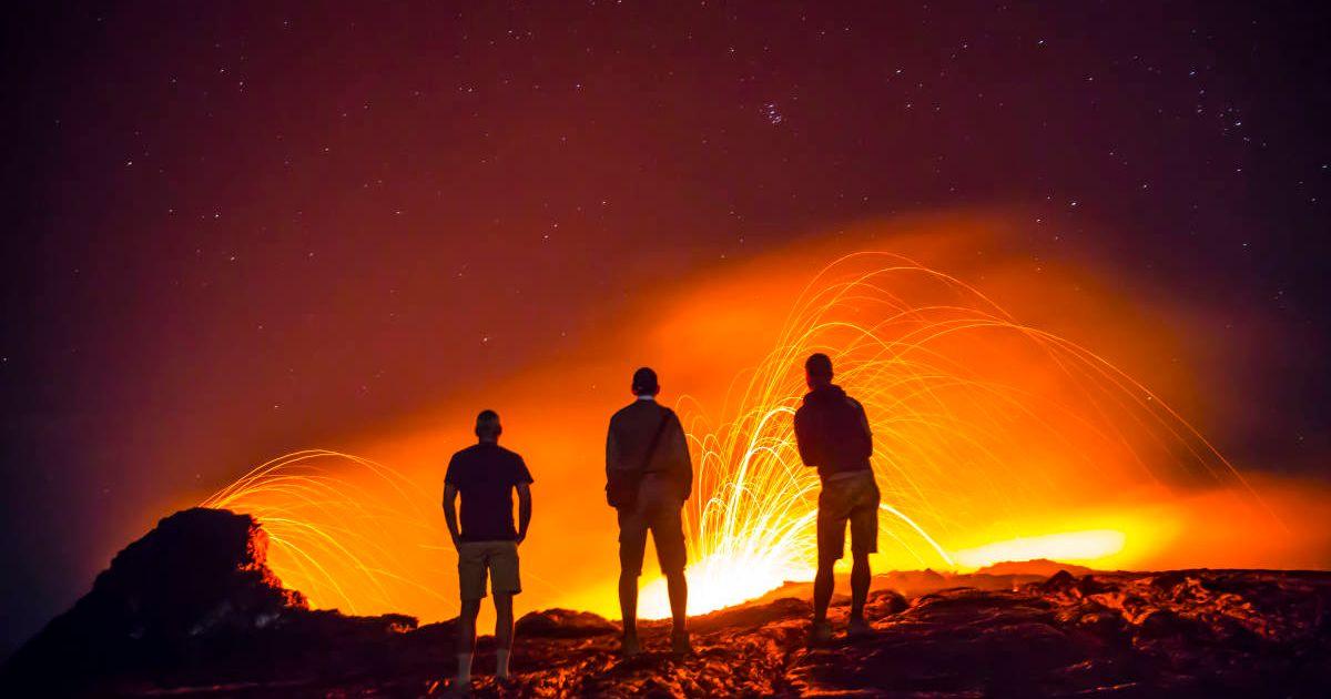 People near a volcano with its surreal glowing lava lake (Representative Cover Image Source: Getty Images | Mike Korostelev)