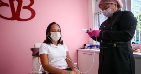 A woman sitting in a chair about to receive ozone therapy from a nurse who specializes in the treatment