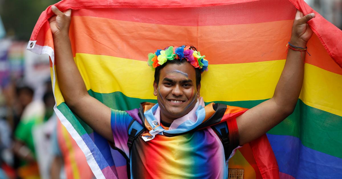 A person holds up a rainbow flag