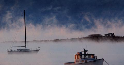 Two boats are pictured on water through a thick haze of Arctic sea smoke