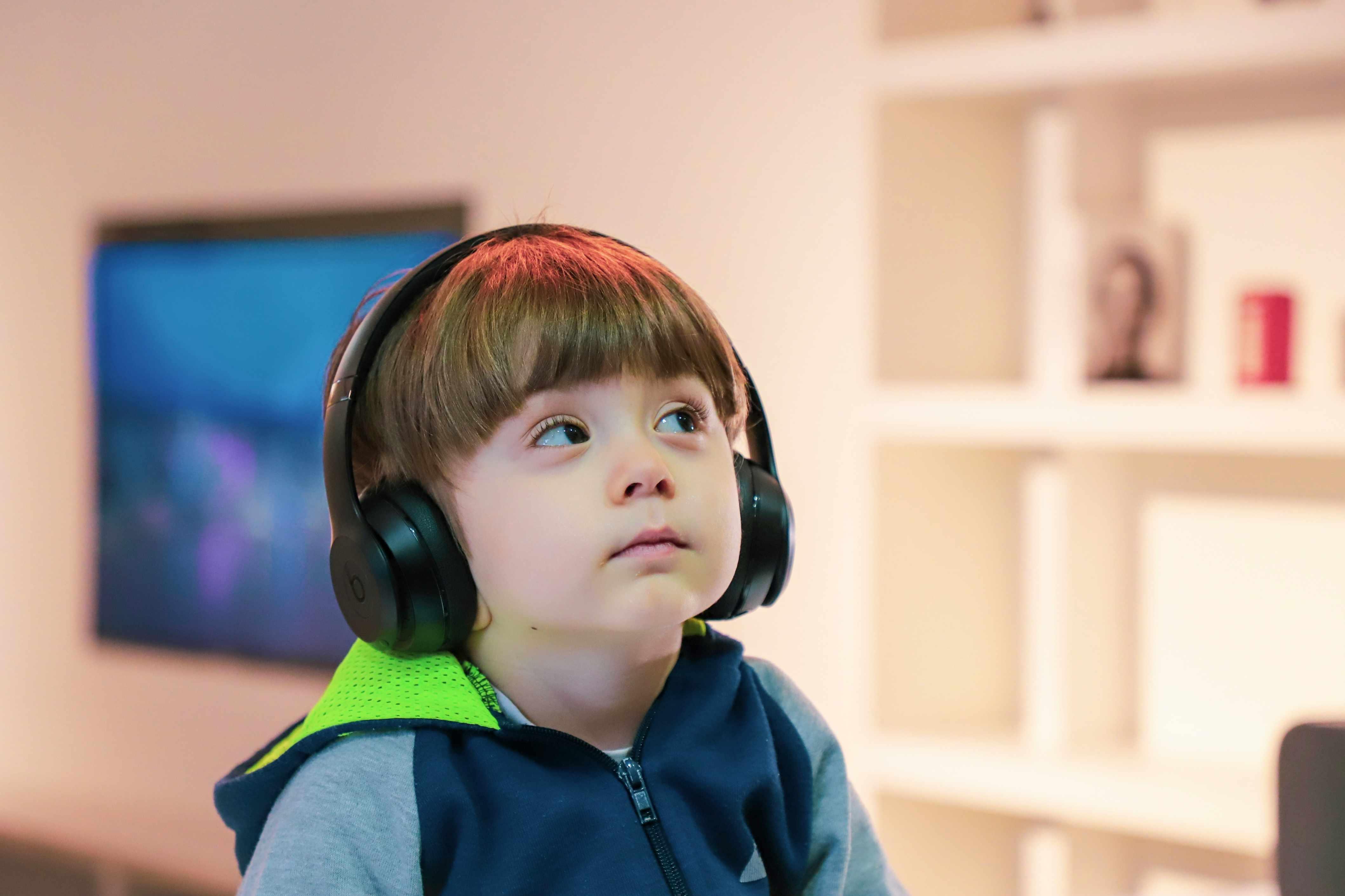 A child is pictured wearing headphones while playing video games.
