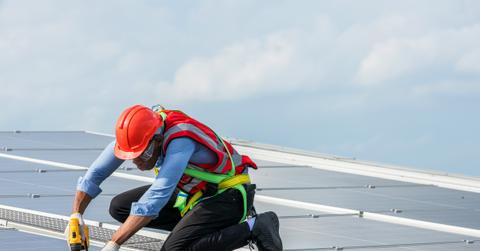 Man working on solar panels on a roof top.