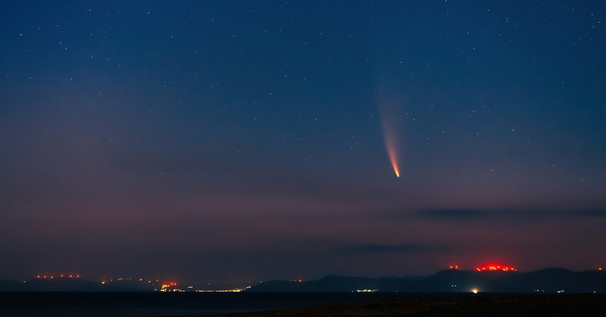 A meteor can be seen lighting up the sky over a city