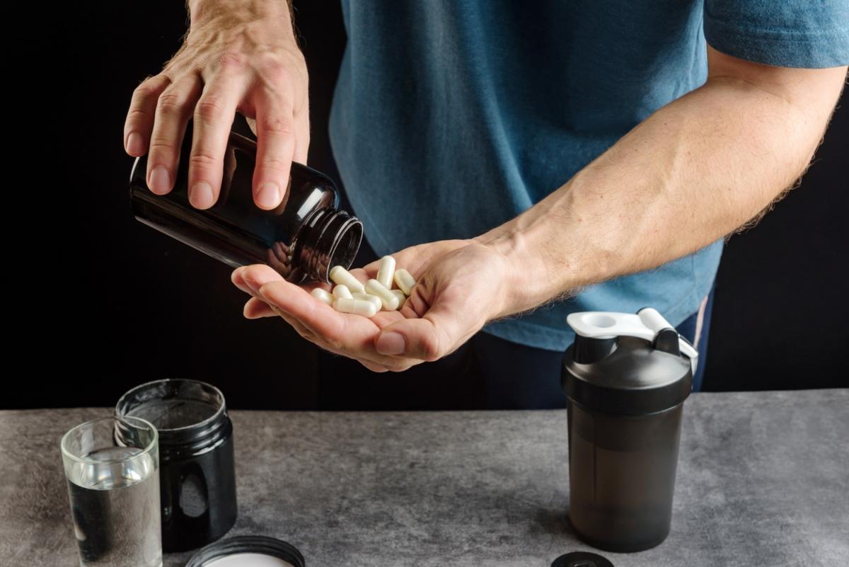 athletic man pouring out capsules into palm