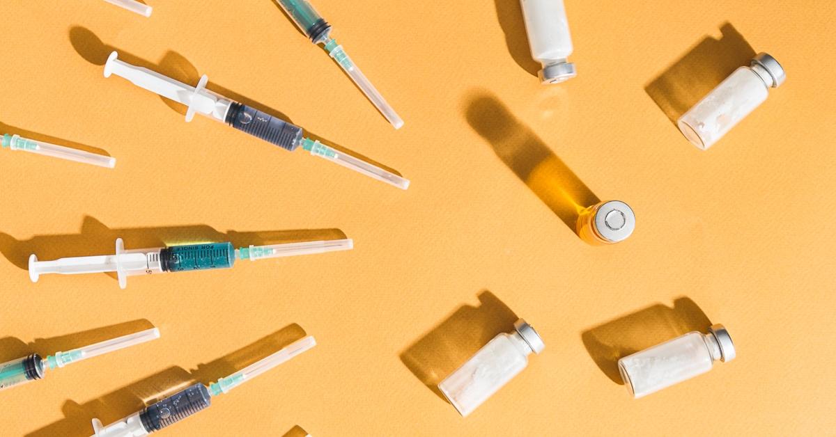 Vaccines and bottles of vaccines with an orange background.