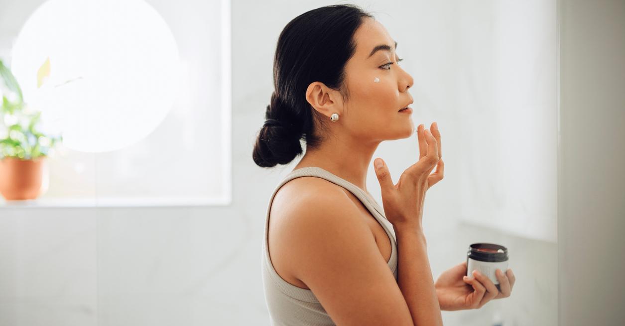 A woman applying face cream.