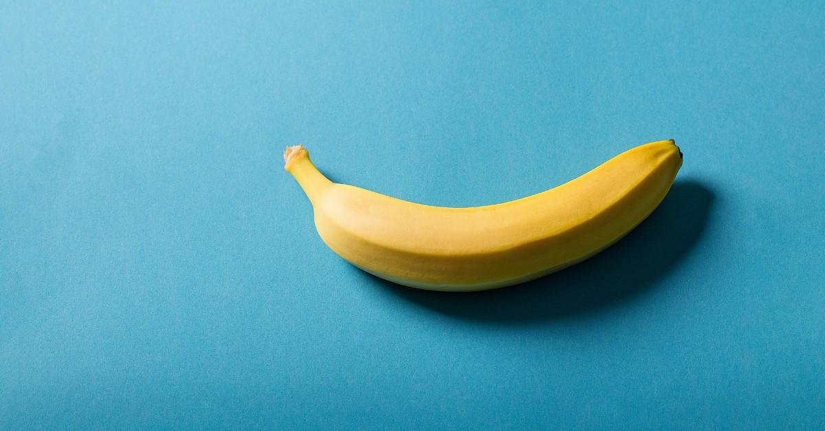 A ripe banana lays on a blue background 