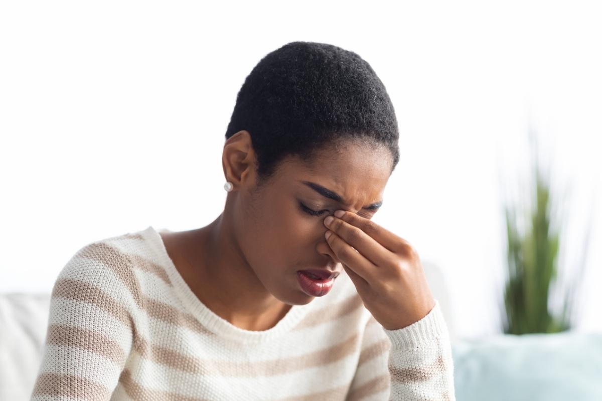 Black woman holding nose due to sinus pain