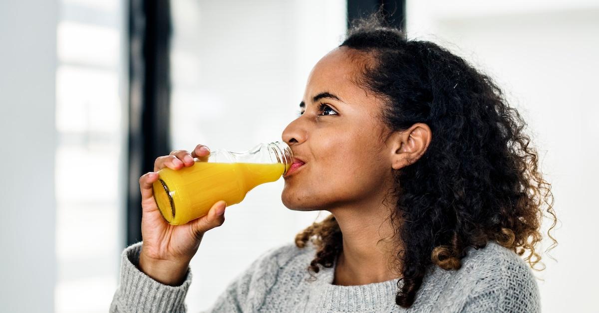 Woman drinking fresh orange juice from glass bottle