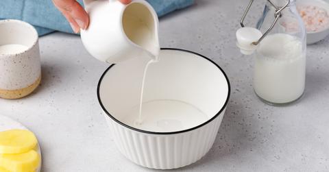 Hand pours cream into ceramic bowl on countertop