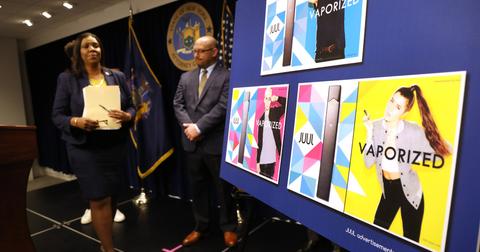 A woman walks in front of a board displaying Juul ads that feature younger people.