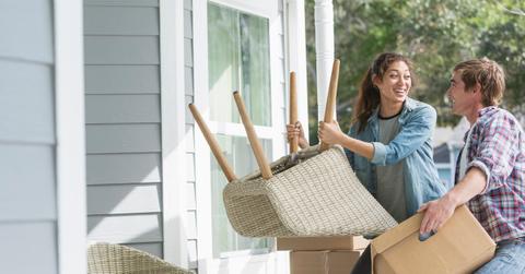Couple moving in with boxes and outdoor chairs.