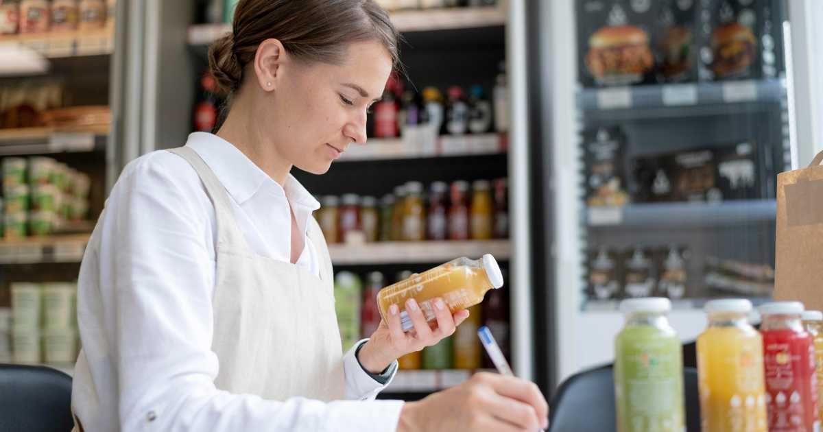 A woman is recording the inventory details of apple juice in a grocery store. (Representative Cover Image Source: Freepik)