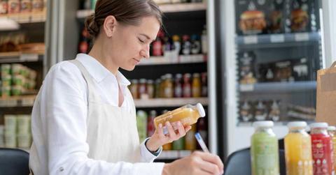 A woman is recording the inventory details of apple juice in a grocery store. (Representative Cover Image Source: Freepik)