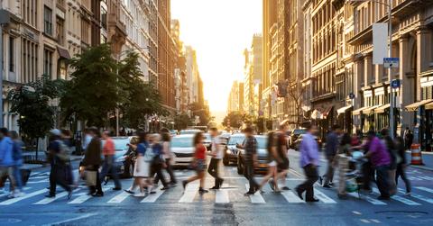 People walking across the crosswalk at the intersection of 23rd Street and 5th Avenue in Manhattan, New York City.