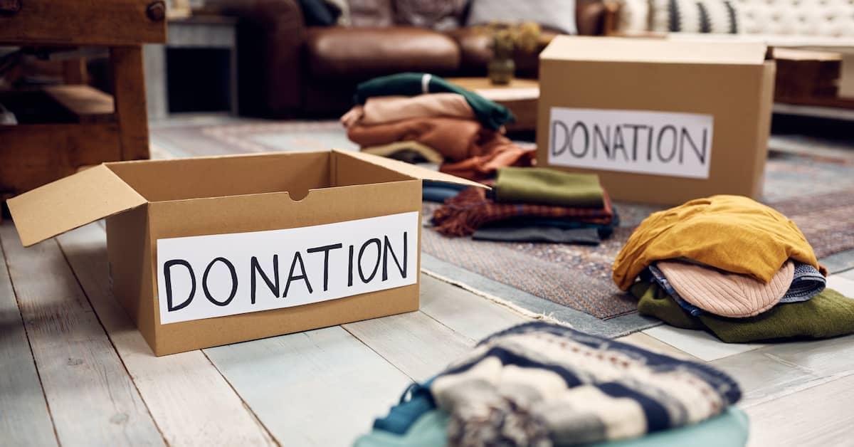 Livingroom with piles of clothes on the floor and two boxes with donation written on the side