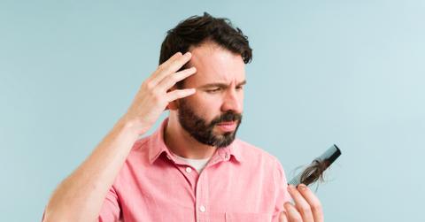 A man is looking at a comb concerned he's losing hair.