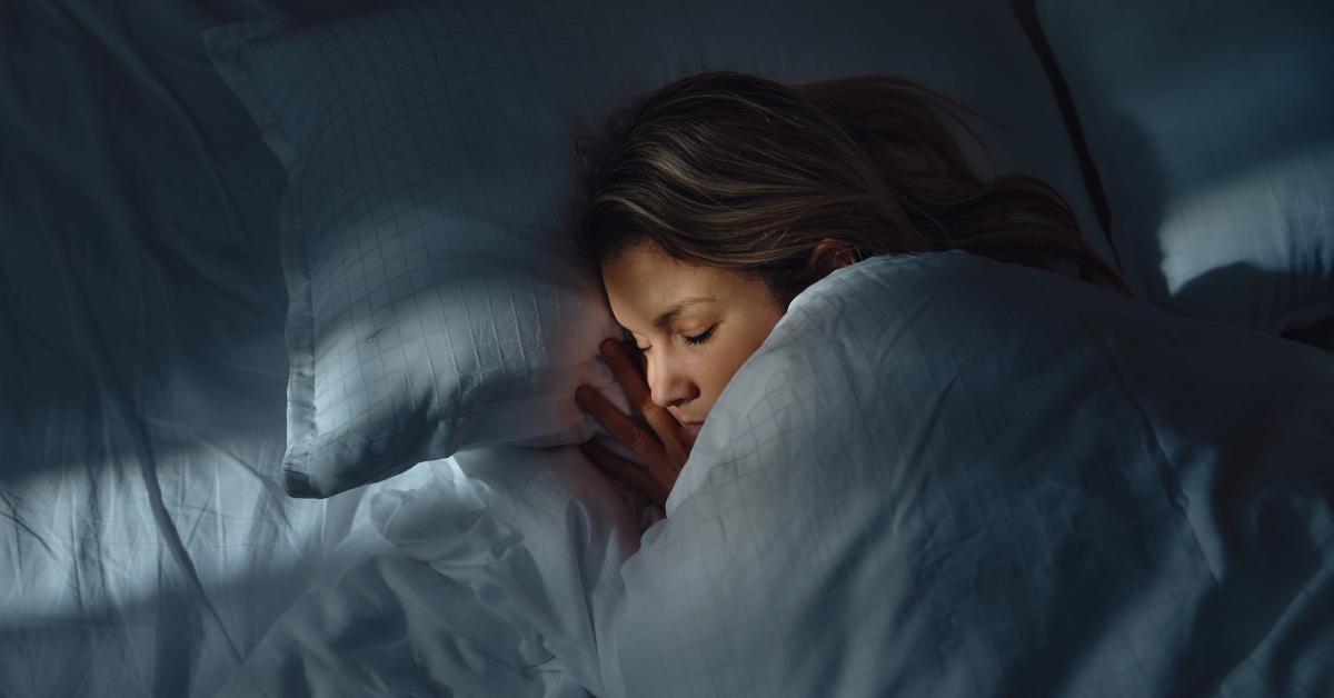 Woman in the dark sleeping under blankets