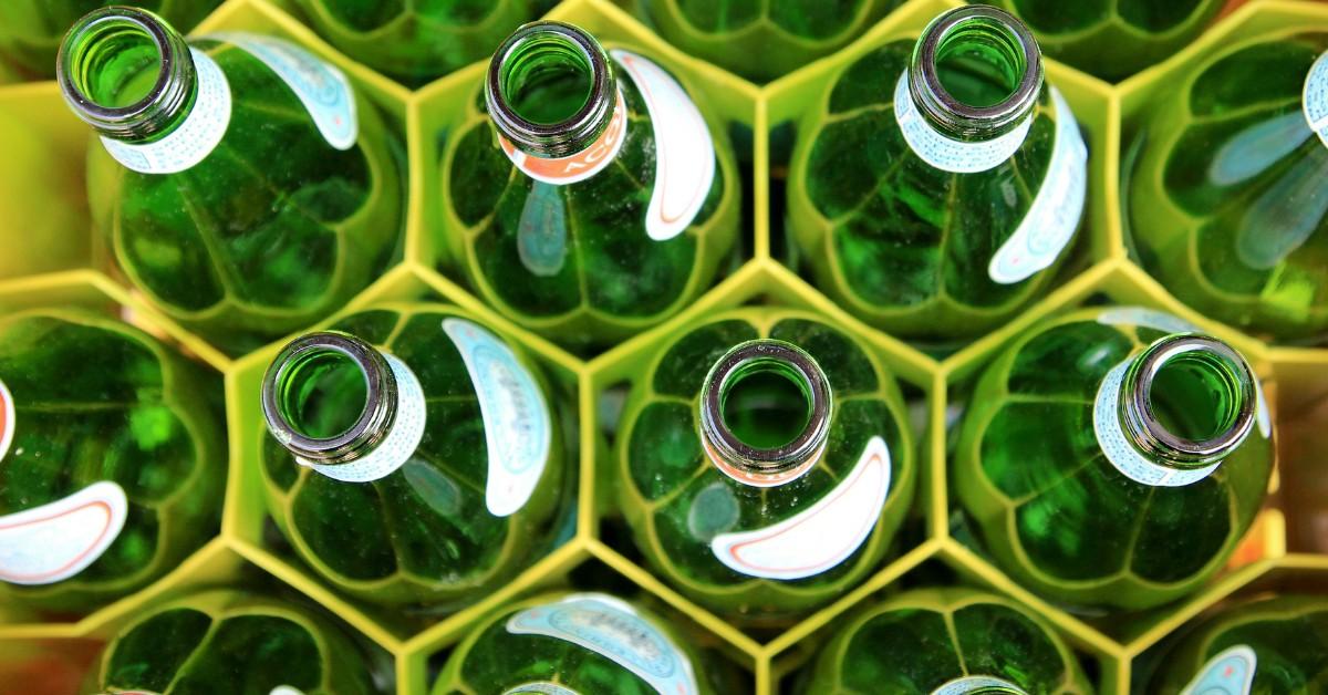 A closeup of the tops of green glass bottles in a production line