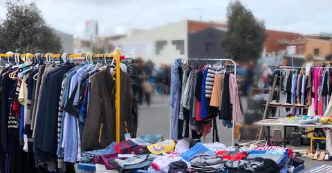 An array of garage sale items on tables and clothing racks outside