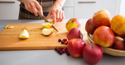 Person chopping apples on a cutting board