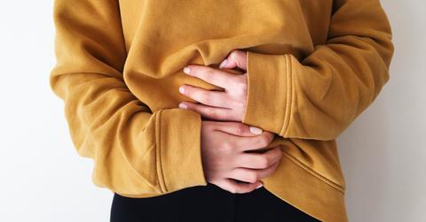 Person clutching their stomach in a yellow sweater