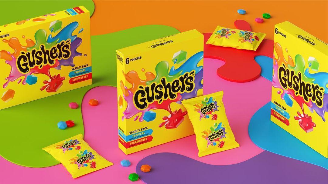 Three boxes of Gushers candy beside packets of Gushers with candy spilled around them.