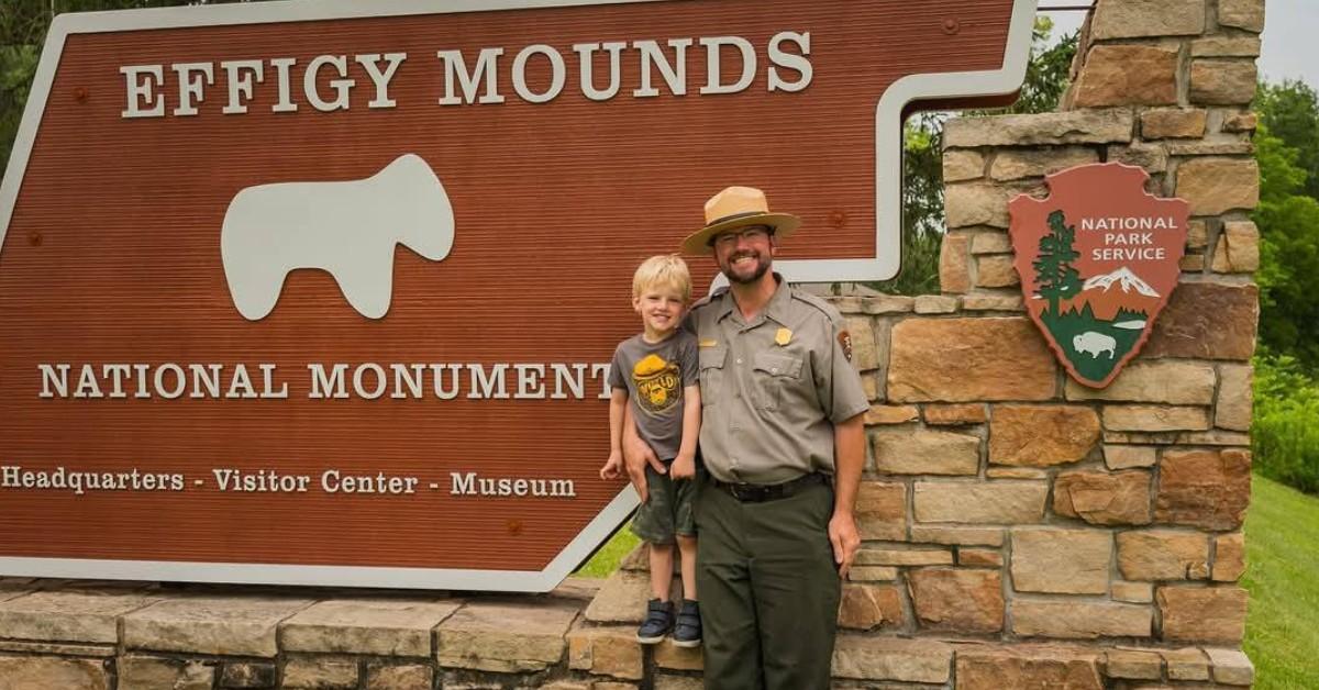 Brian Gibbs poses in front of the Effigy Mounds National Monument sigh with his son