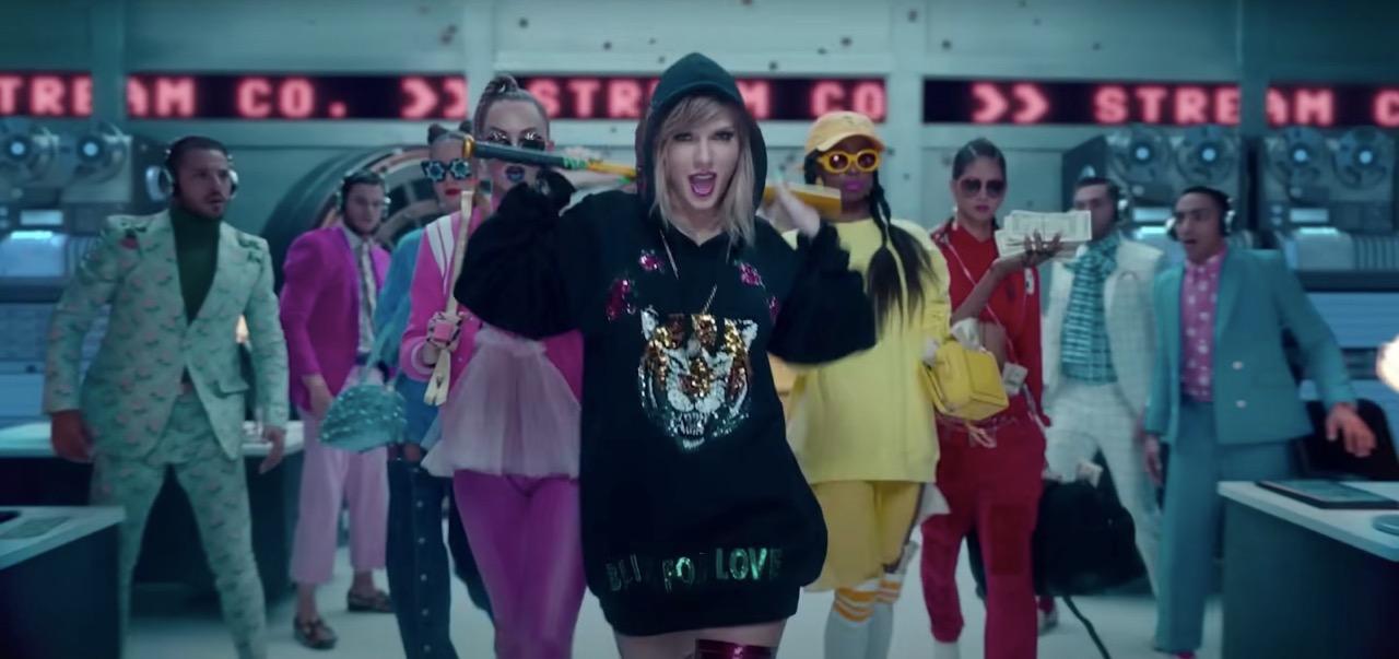 Taylor Swift in her "Look What You Made Me Do" music video carrying a baseball bat while wearing a black hoodie with a sparkly tiger on the front