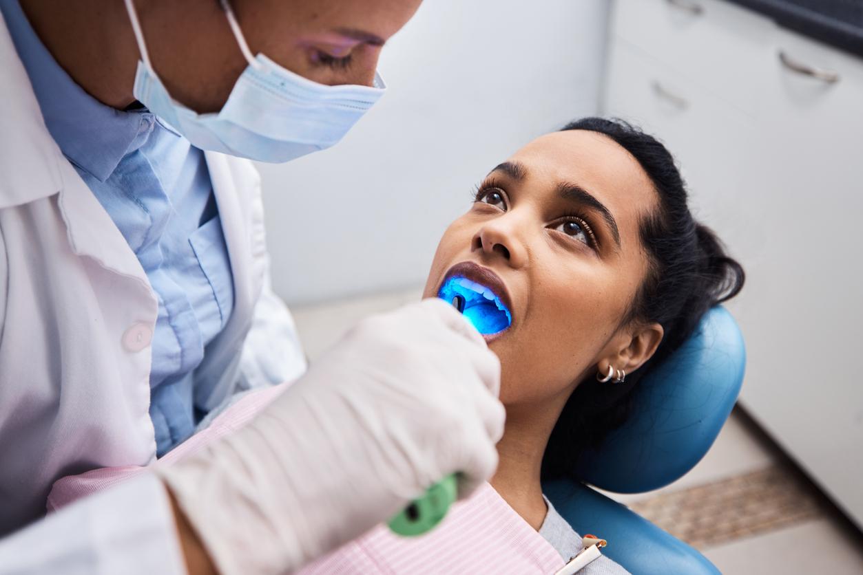 A dentist utilizes a light-emitting device in a patient's mouth.