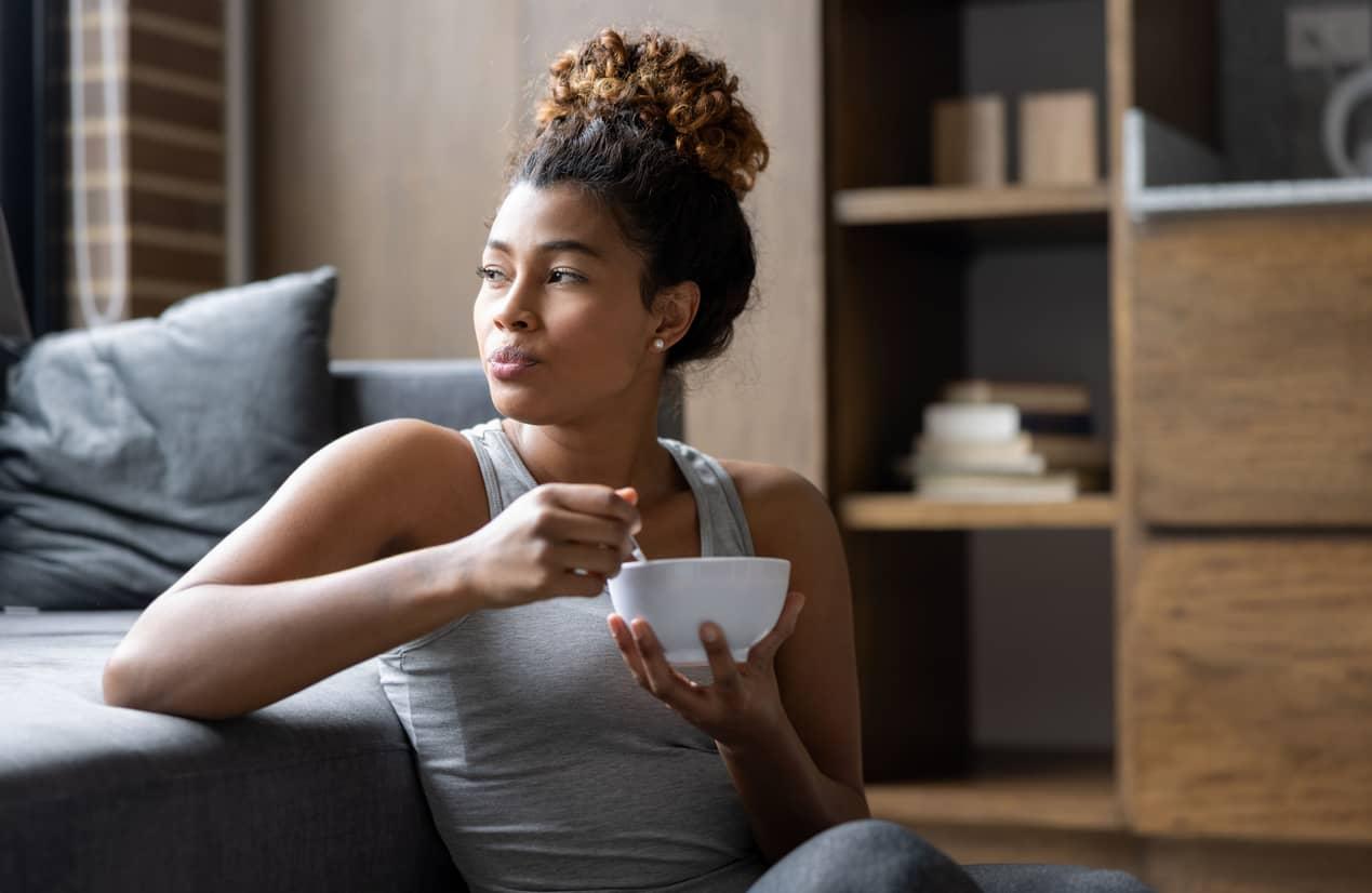 Young person enjoying breakfast in the livingroom while gazing out the window.