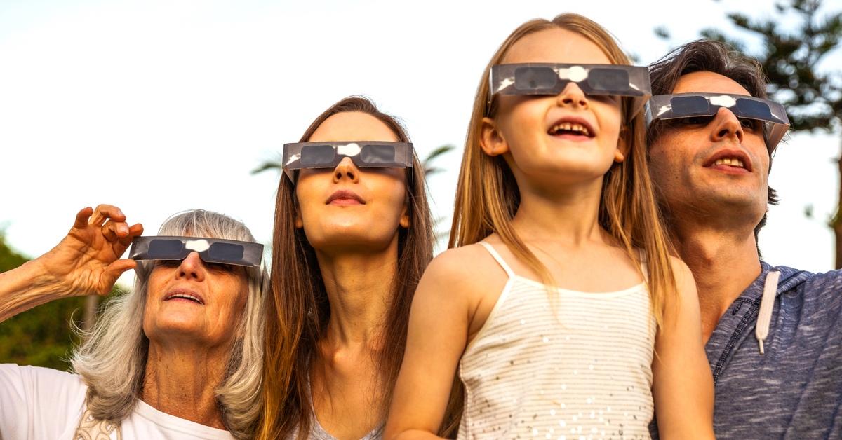 Family wearing solar eclipse glasses outside. 