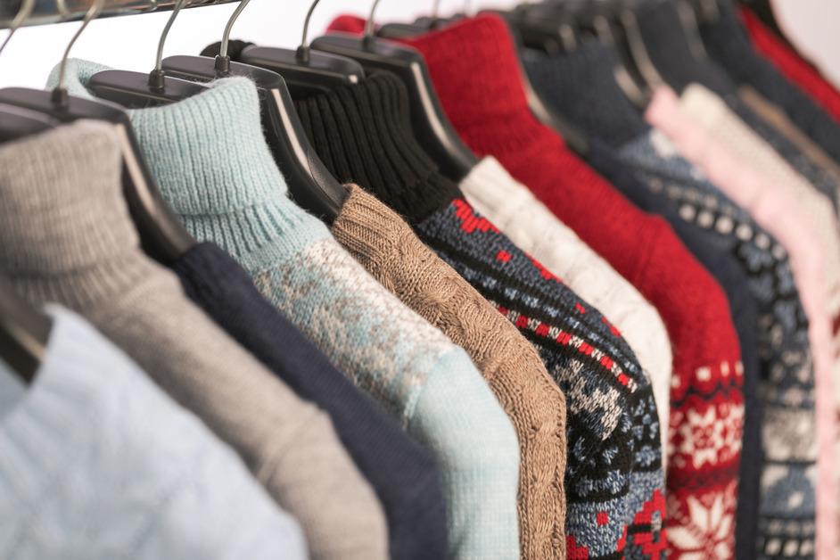 A rack of secondhand sweaters at a thrift store.