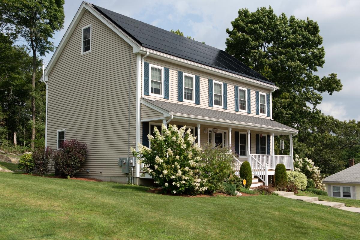 tan 2-story house with green shutters and solar panels