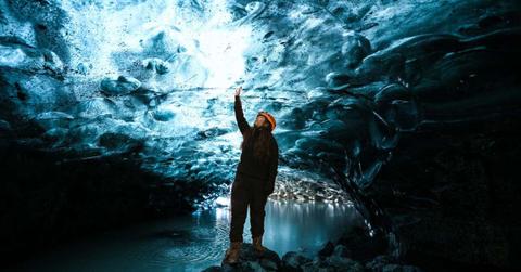 A researcher standing inside an ice cave with a lake inside it. (Representative Cover Image Source: Pexels | Priyanka Varlani)