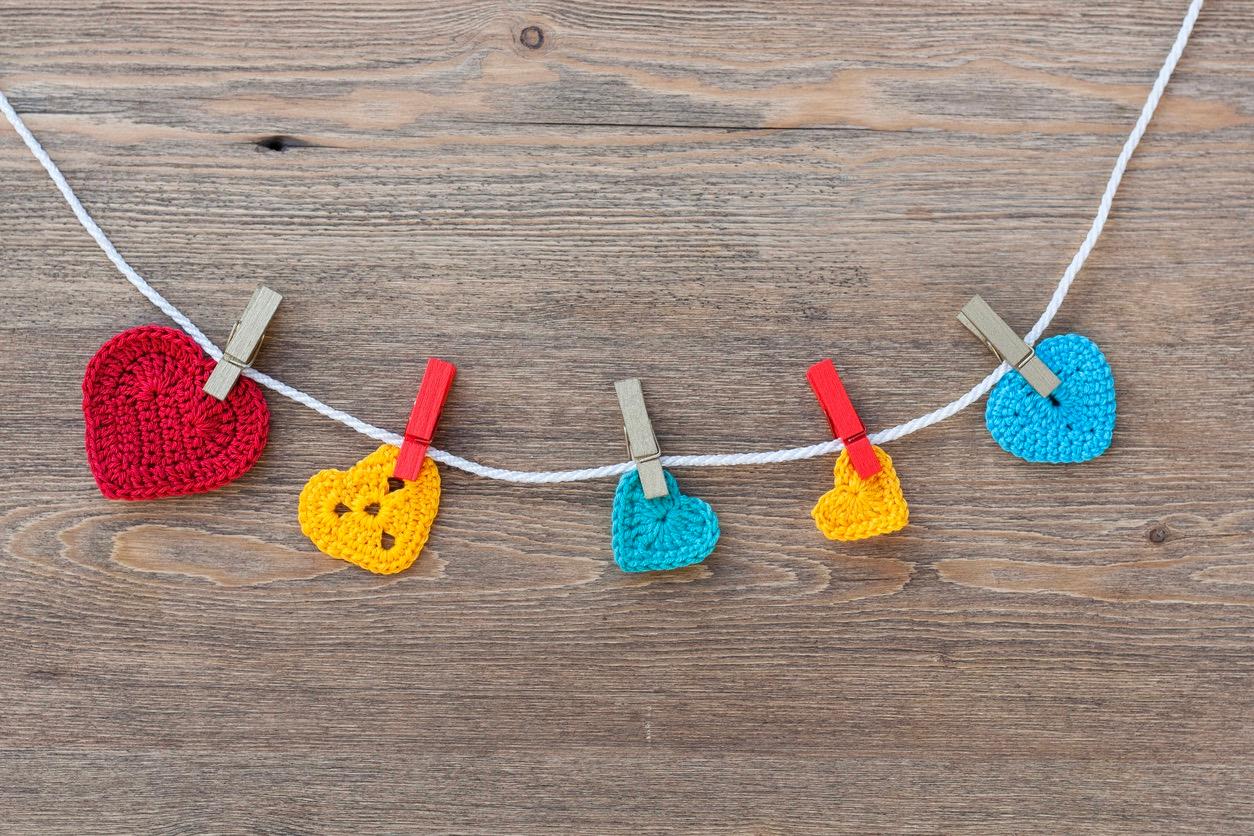 Red, yellow, and blue crochet hearts attached to a string with clothespins to create a garland.