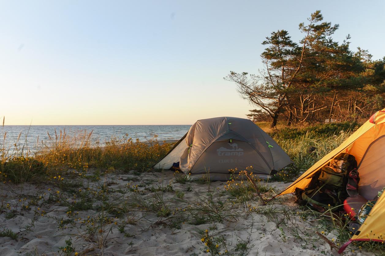 Two tents set up along a lakeshore during sunset